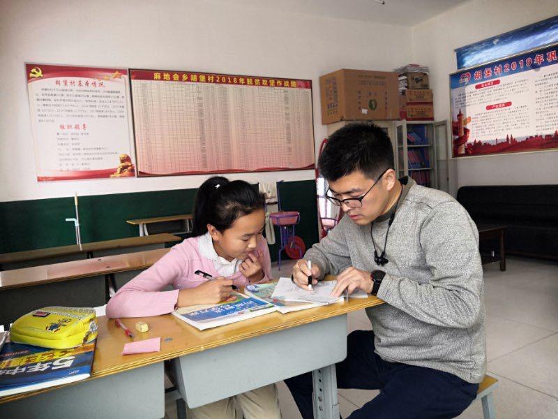 吴克友正在辅导村里小朋友学习